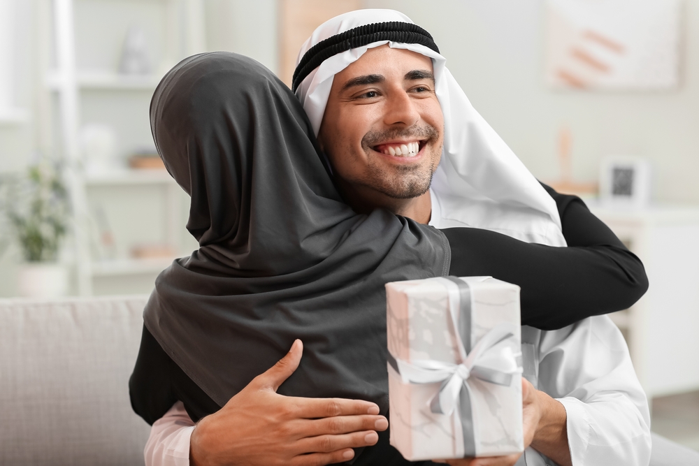 father hugging child warmly while handing the child a gift