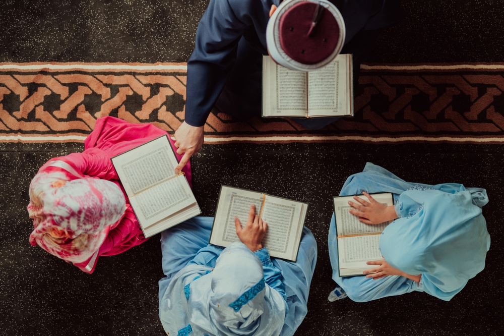 kids are sitting down around their teacher inside a masjid reading quran in the last 10 nights of Ramadan