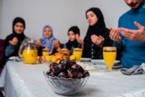 A family gathered around the dinner table with their hands up praying praying