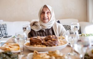 when is Eid al-Adha? An elderly lady enjoys a heartly meal with her family