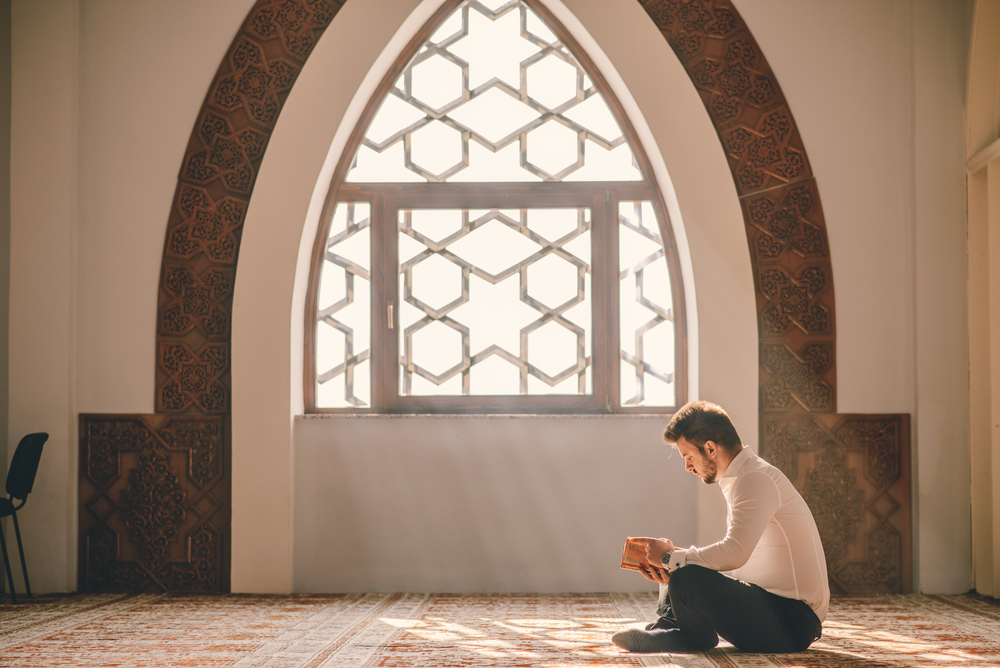 fidya vs kaffarah. man sitting in side of a masjid prostrating his hands in the air making dua